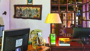 Een kamer met een bureau, computer, lamp, kunstwerk in een lijst en een plank met decoratieve objecten.