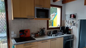 A kitchen with wooden cabinets, a microwave, a coffee maker, and a sink. - House in vacation residence 4 persons swimming pool, tennis, petanque, sneakers (Saint-Julien-en-Born)