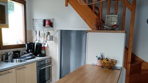 A kitchen with a wooden table, a refrigerator, and a sink. - House in vacation residence 4 persons swimming pool, tennis, petanque, sneakers (Saint-Julien-en-Born)