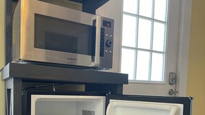 A compact refrigerator with a microwave on top, a freezer compartment, and a door with a window.