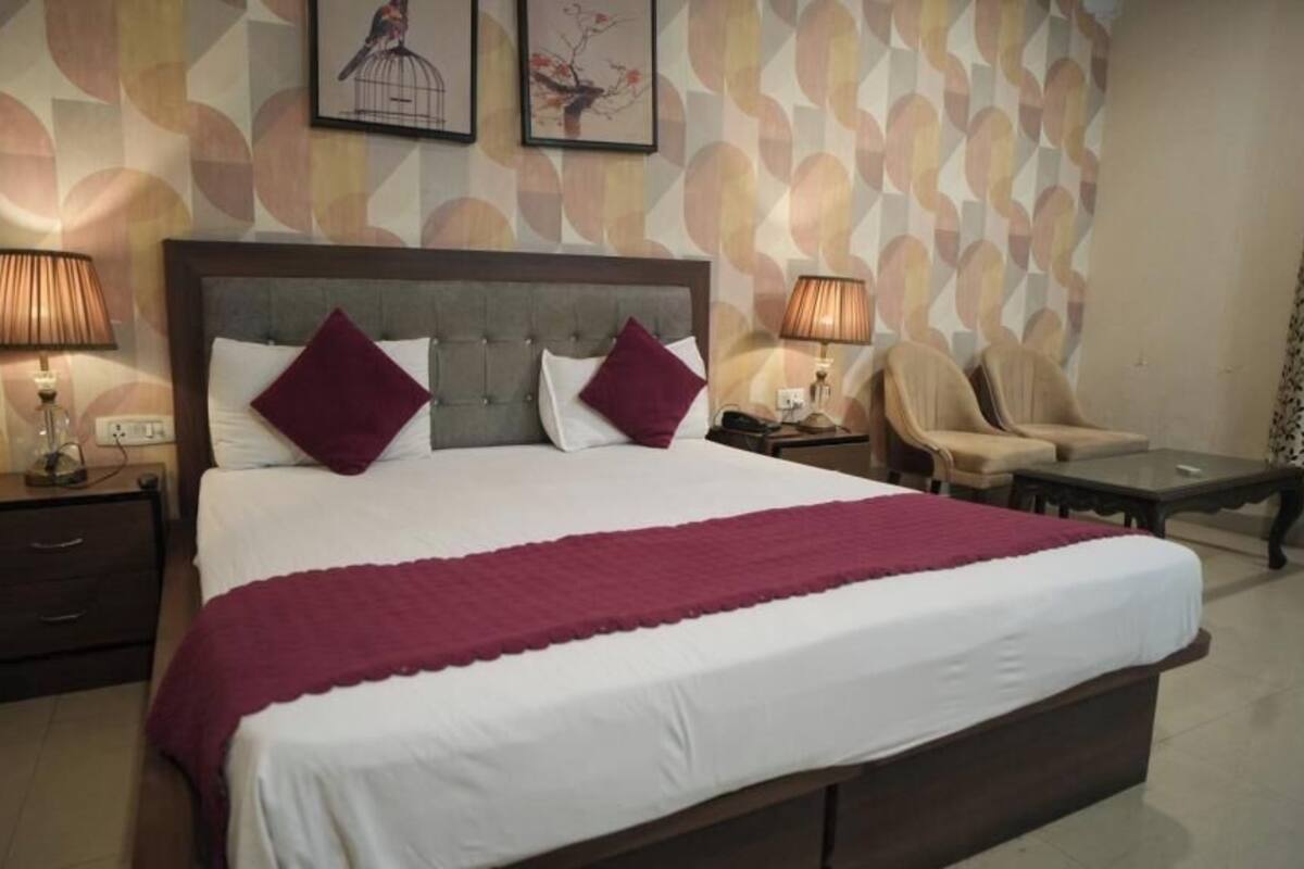 Ein Hotelzimmer mit einem großen Bett, zwei Nachttischen mit Lampen, einem Sessel und einem kleinen Tisch.