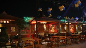Un restaurant en plein air avec des tables et des chaises en bois, décoré de ballons.
