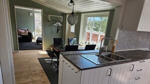 A modern kitchen with a central island, white cabinetry, and a large window providing a view of the outdoors.
