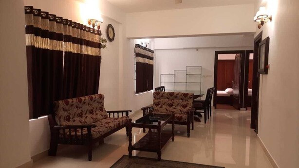 A living room with a sofa set, a coffee table, and a rug. There is a ceiling fan and a wall-mounted light fixture.