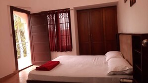 A bedroom with a bed, a wardrobe, a door, and a window with curtains.