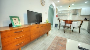 Eine moderne Küche mit weißen Schränken, einem Holztisch und einem Fernseher auf einer Holzkommode.