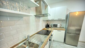 Eine moderne Küche mit Spüle aus Edelstahl, einer Mikrowelle, einem Einbauofen und einem Kühlschrank.