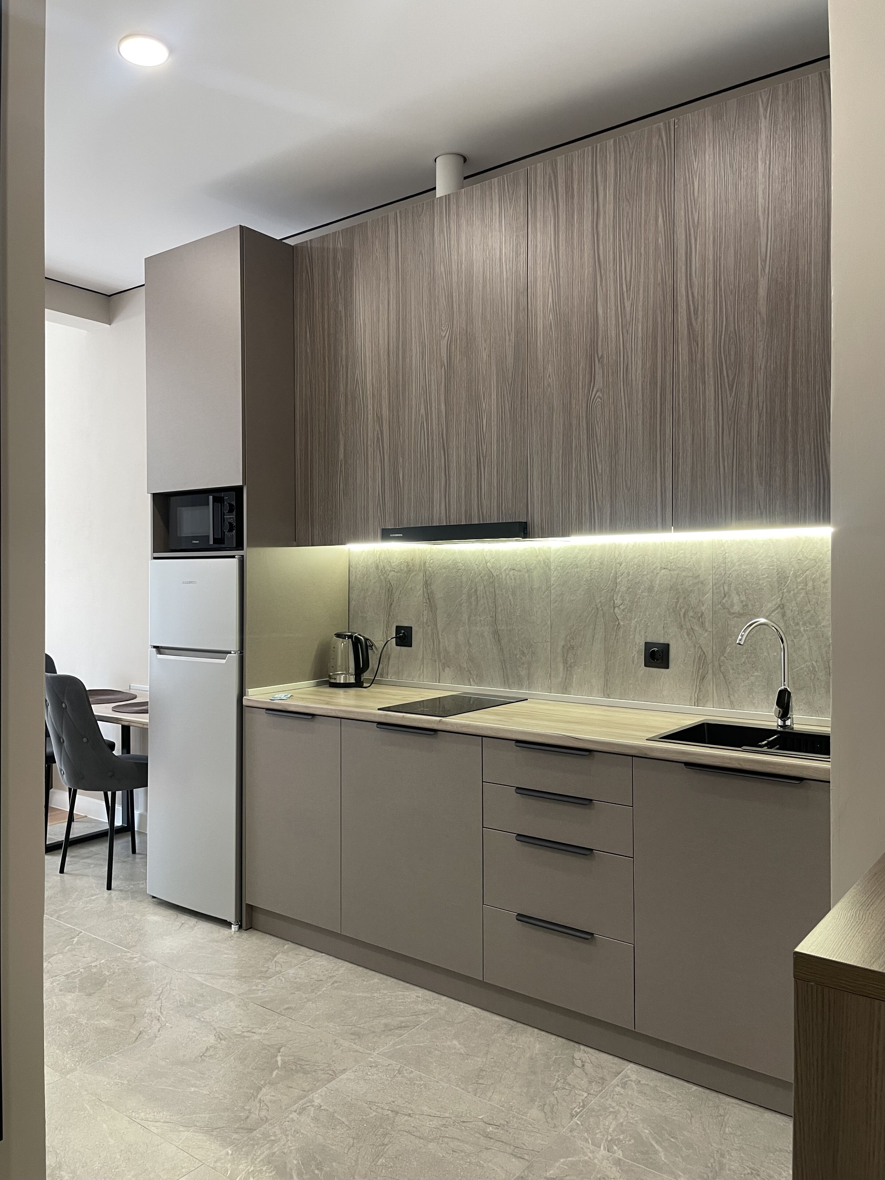 A modern kitchen with a built-in microwave, a kettle, and a sink.