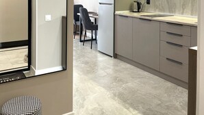 A modern kitchen with a built-in microwave, a refrigerator, and a sink. There is a dining area with a table and chairs visible in the background.