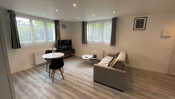 A modern living room with a sofa, a dining table, and a TV. - Separate F2 near RER&TGV and amenities (Massy)