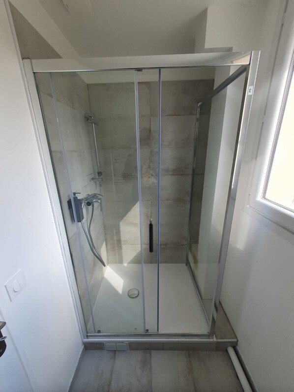 A glass-enclosed shower with a tiled floor and a visible showerhead.