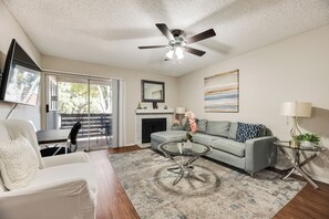 A living room with a ceiling fan, a fireplace, a sofa, a coffee table, and a television.