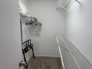 A small, enclosed storage area with a metal shelf, a hanging rack, and a carpeted floor. - I207 - Apt|Patio|10mi to Convention Ctr|Sleeps 2 (Irving)
