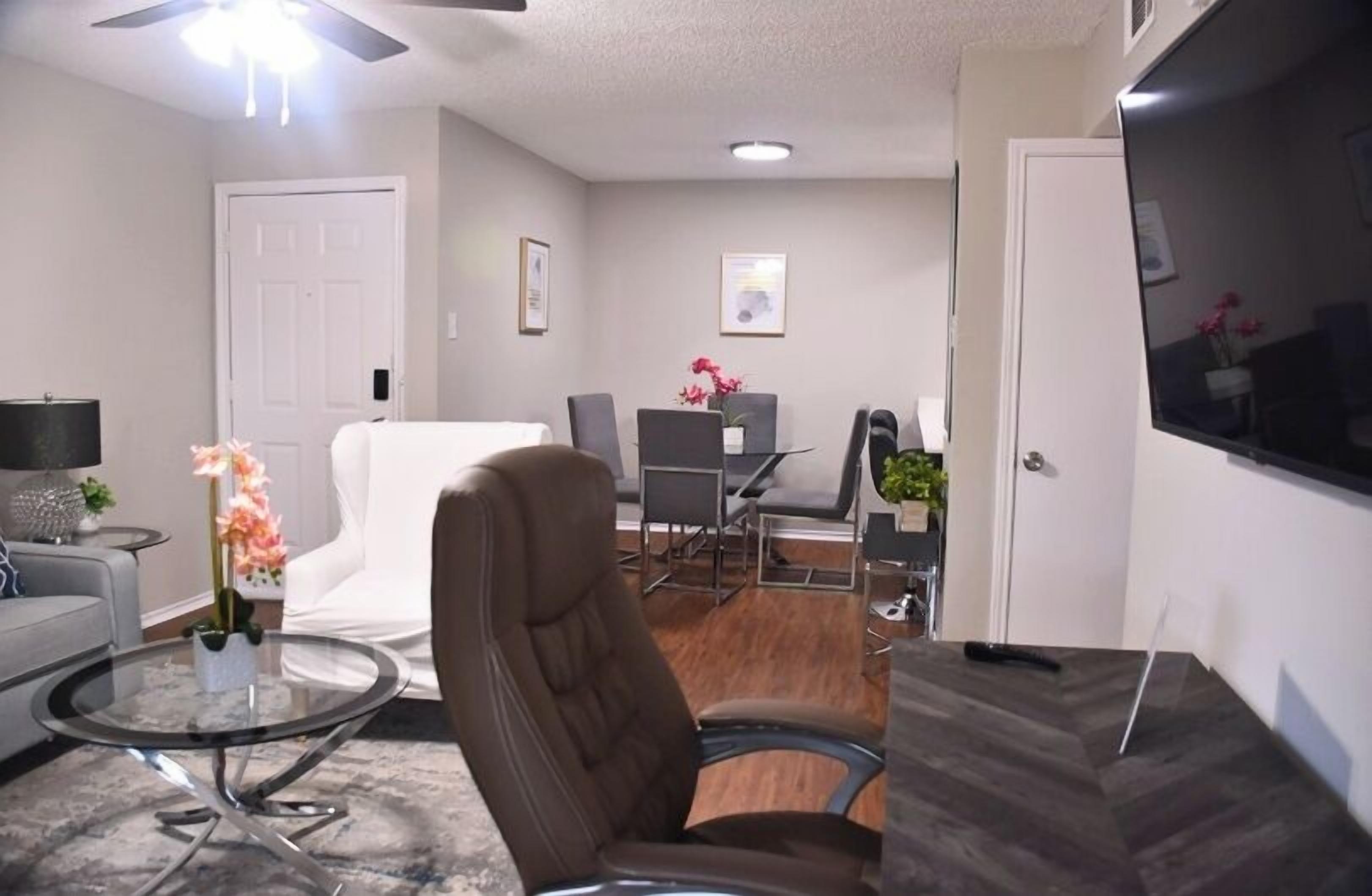 A living room with a sofa, armchair, coffee table, and a dining area with chairs and a table.