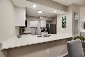 A modern kitchen with a central island, built-in appliances, and recessed ceiling lights.