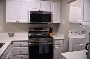 A kitchen with white cabinets, a microwave, a double oven, and a stove.
