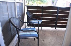 A covered patio area with two chairs and a wooden fence. - I207 - Apt|Patio|10mi to Convention Ctr|Sleeps 2 (Irving)