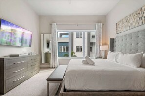 Habitación de hotel moderna con una cama grande, un televisor de pantalla plana, un aparador y vistas al exterior.