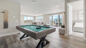A modern living room with a pool table, a sofa, and a bed. - Golf View Penthouse w/ Rooftop Terrace Near Disney (Kissimmee)