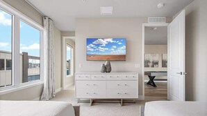 A bedroom with a large window, a flat-screen TV, a dresser, and a pool table in the adjacent room. - Golf View Penthouse w/ Rooftop Terrace Near Disney (Kissimmee)