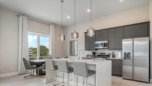 A modern kitchen with a central island, stainless steel appliances, and pendant lighting. - Golf View Penthouse w/ Rooftop Terrace Near Disney (Kissimmee)