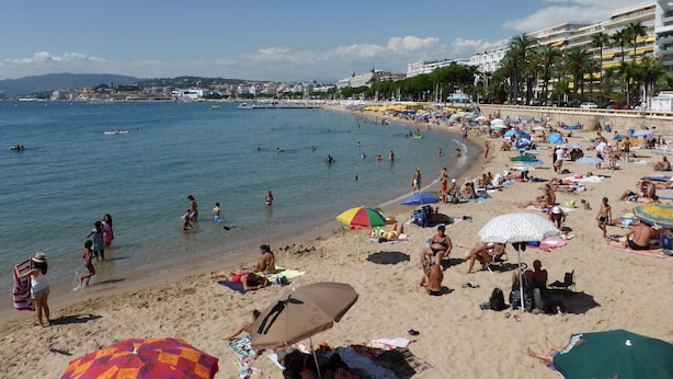 A crowded beach with people sunbathing and swimming, umbrellas, and a cityscape in the background. - Beautiful Apartment in the heart of Palm Beach, Cannes (Cannes)