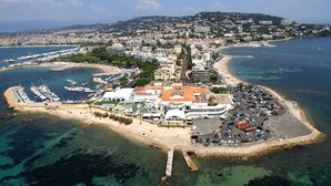 An aerial view of a coastal town with a marina, a beach, and a central building with a red roof. - Beautiful Apartment in the heart of Palm Beach, Cannes (Cannes)