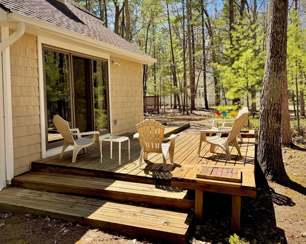 A wooden deck with outdoor seating and a glass door leading to a covered area.