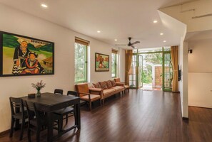 A spacious living area with a dining table, sofa, and artwork on the walls.