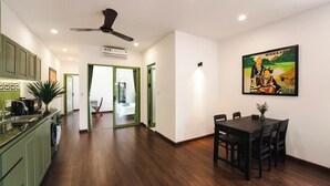 Una cocina moderna con gabinetes verdes, un comedor con mesa de madera oscura y un ventilador de techo.