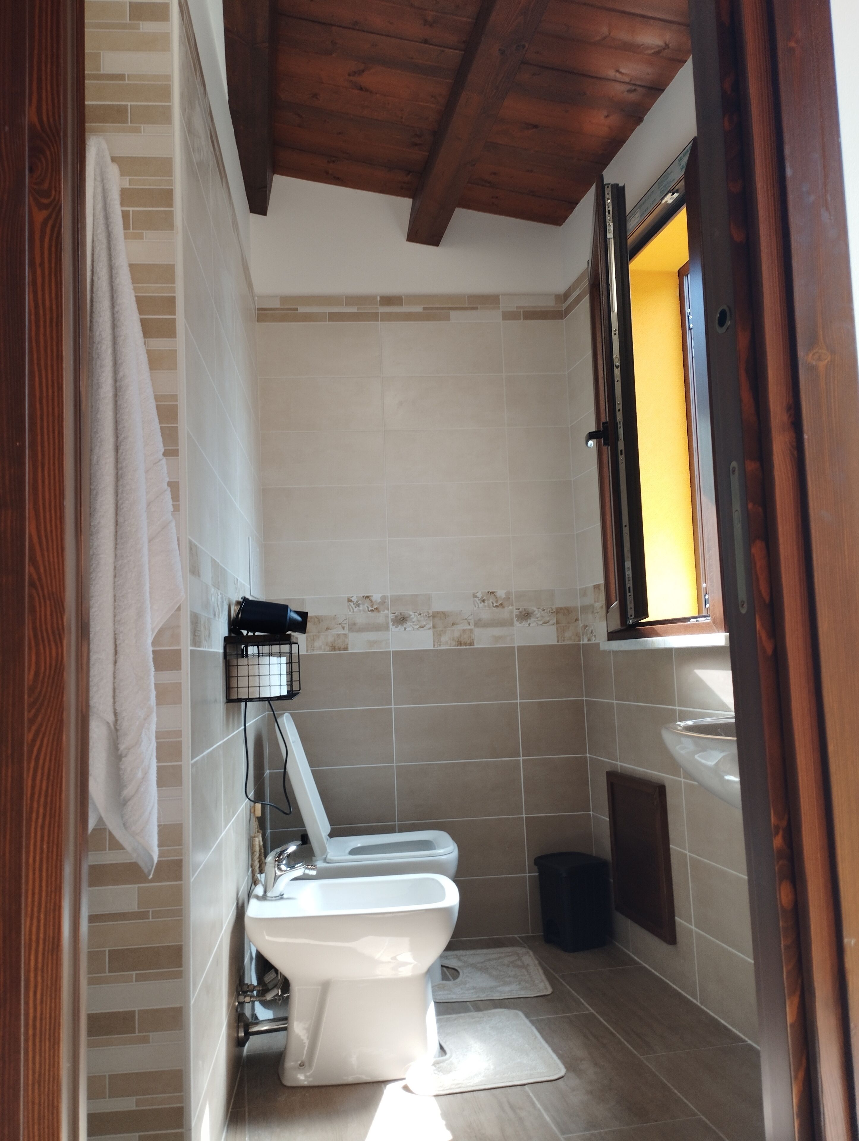 Ein Badezimmer mit Toilette, Waschbecken und einem Fenster mit Außenblick.