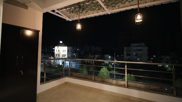 A balcony with a metal railing and a view of the city at night.
