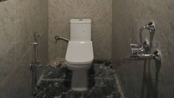 A modern bathroom with a toilet, a shower, and a hand dryer.