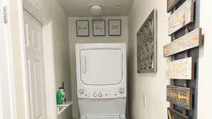 A laundry room with a front-loading washer and dryer, a white door, and motivational signs on the wall.