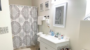 A bathroom with a white vanity, a shower curtain with a black and white pattern, a mirror, and a toilet.