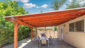 Une terrasse extérieure dotée d’une pergola en bois, d’une table et de chaises.