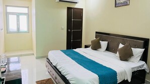 A hotel room with a bed, bedside table, and a ceiling fan. - Hotel The Majestic Taj (Agra)