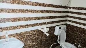 A bathroom with a sink, toilet, and a bucket on the floor. - Hotel The Majestic Taj (Agra)