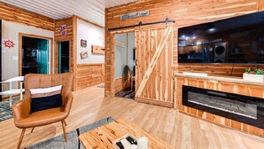 Ein gemütliches Zimmer mit Holzvertäfelung, einem Kamin, einem Sofa und einem Schreibtisch mit Computer.