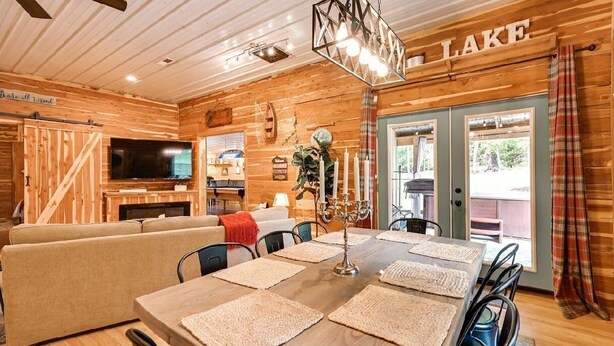 Ein gemütliches Blockhaus-Interieur mit einem Esstisch für vier Personen, einer Couch, einem Fernseher und einem Schild mit der Aufschrift 'LAKE'.