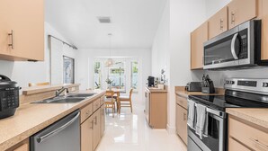 A modern kitchen with stainless steel appliances, wooden cabinets, and a central island with seating.