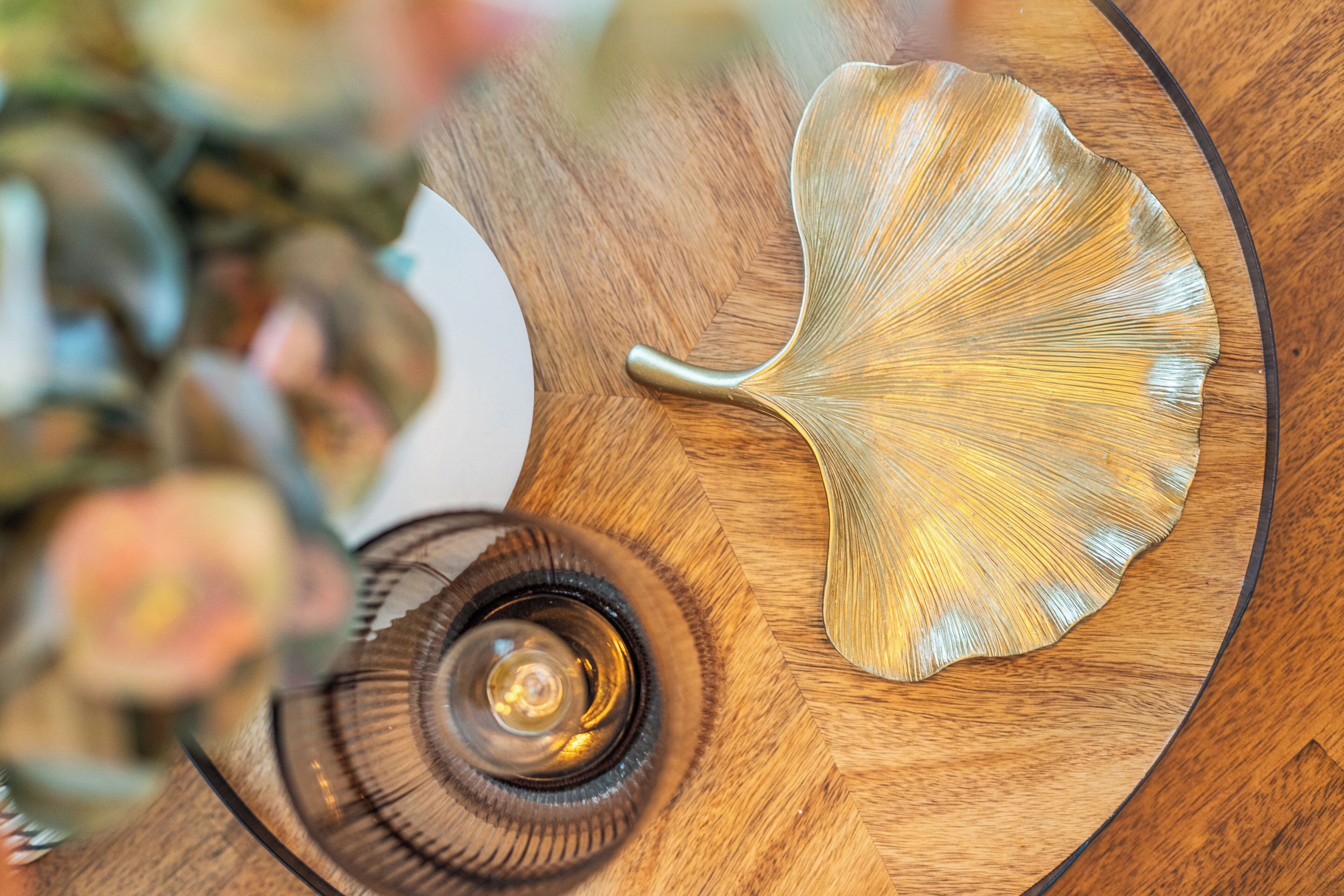 Una mesa de madera con cubierta de vidrio, una pieza decorativa con forma de hoja y un objeto de vidrio en espiral.