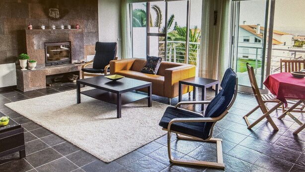 A living room with a fireplace, a sofa, a coffee table, and a dining area with a table and chairs. - PORTO MARTINS RELAX APARTMENT - AL (Porto Martins)