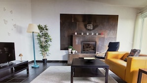 A modern living room with a fireplace, a sofa, a coffee table, and a TV. - PORTO MARTINS RELAX APARTMENT - AL (Porto Martins)