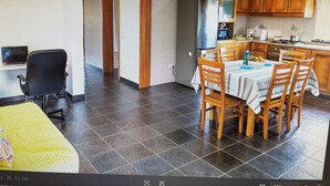 A spacious kitchen with wooden cabinets, a dining table with chairs, and a refrigerator. - PORTO MARTINS RELAX APARTMENT - AL (Porto Martins)