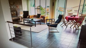 A spacious living area with a sofa set, a dining table with chairs, and a balcony with a view. - PORTO MARTINS RELAX APARTMENT - AL (Porto Martins)