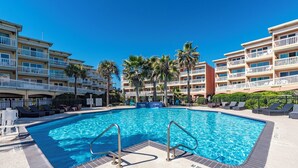 A swimming pool with no diving sign, surrounded by lounge chairs and palm trees, with hotel buildings in the background. - Galveston condo on Seawall near beach, gulf view, pools, WiFi, fitness room. (Galveston)