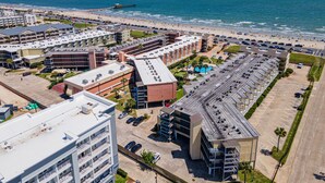 A coastal hotel with multiple buildings, a parking lot, and a beach view. - Galveston condo on Seawall near beach, gulf view, pools, WiFi, fitness room. (Galveston)