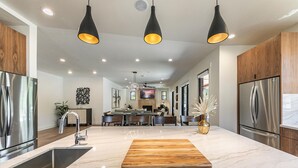 A modern kitchen with a marble countertop, stainless steel appliances, and a central island. - Aloha Mountain Haus | Luxury Golf Retreat | Club Access | Billiards (Truckee)