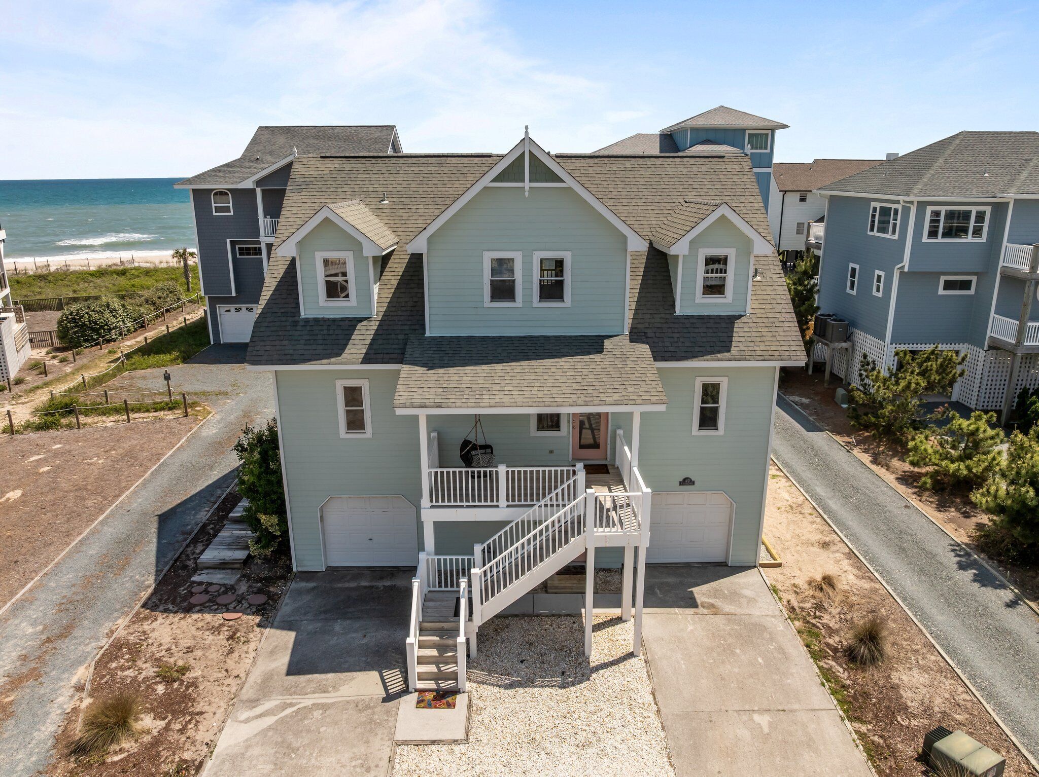 A two-story house with a front porch, a garage, and a view of the ocean.